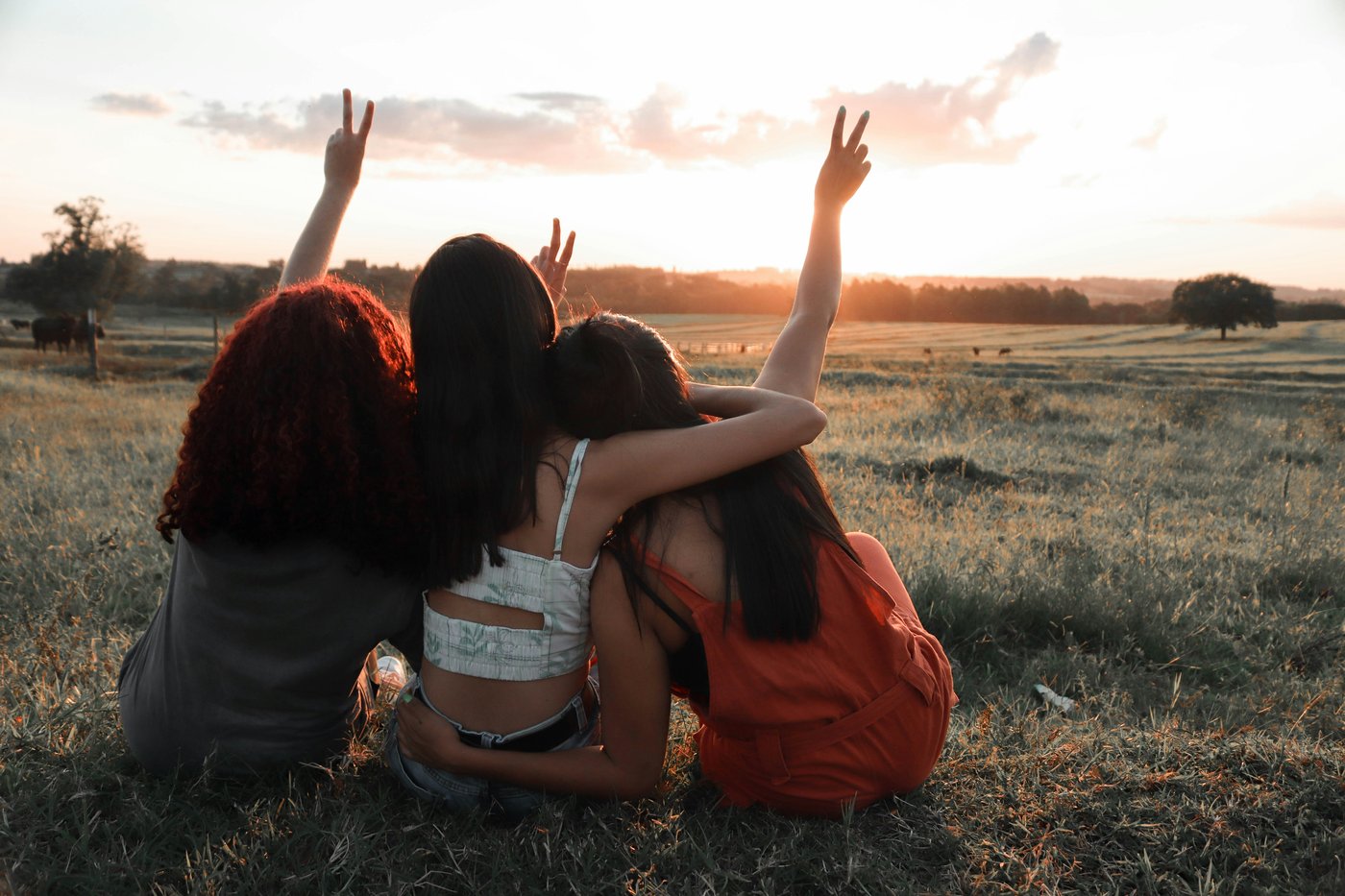 Friends sitting together in a field at sunset, phones nowhere in sight